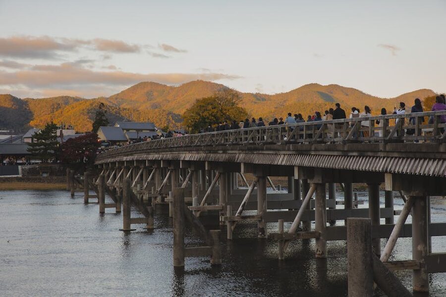 Crowds walking on Togetsukyo Bridge in Arashiyama Kyoto at sundown
