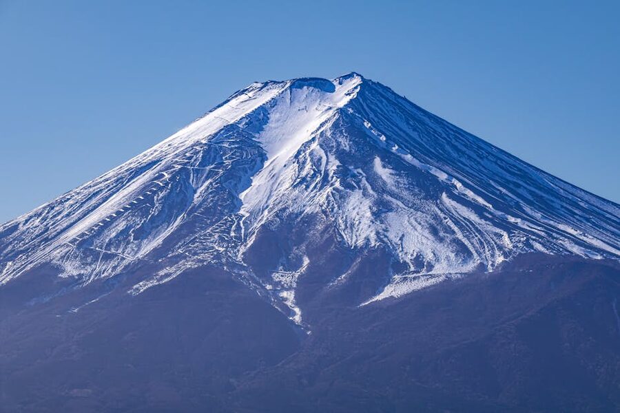Mt Fuji on a clear winter day with snow on the cone and clouds drifting beneath