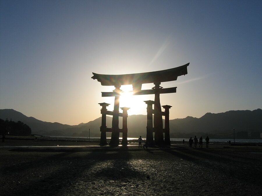 Itsukushima torii at low tide with people walking on the sand flats