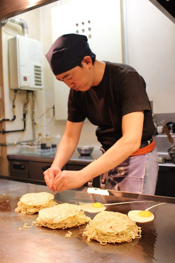 Chef preparing Hiroshima okonomiyaki on the iron
