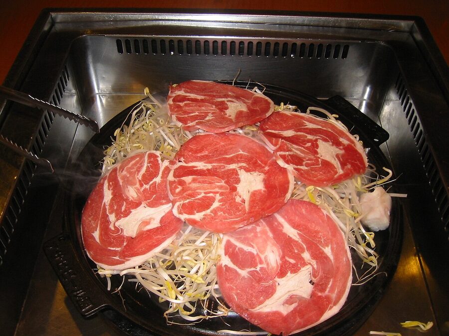 Lamb and vegetables grilling on a domed jingisukan pan.