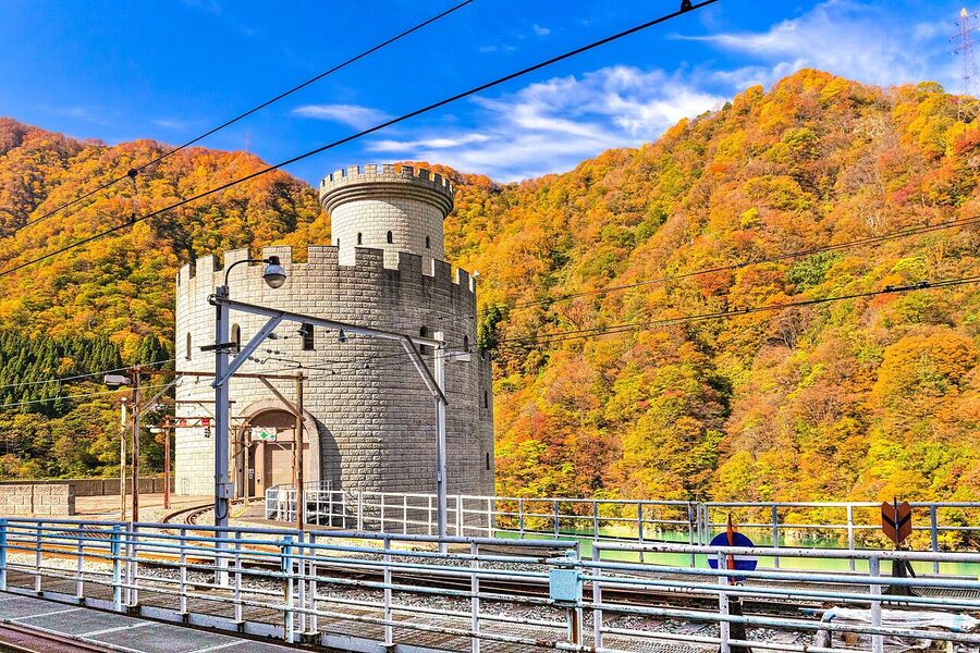 An autumn scene at the Kurobe Gorge Railway with foliage along the rails