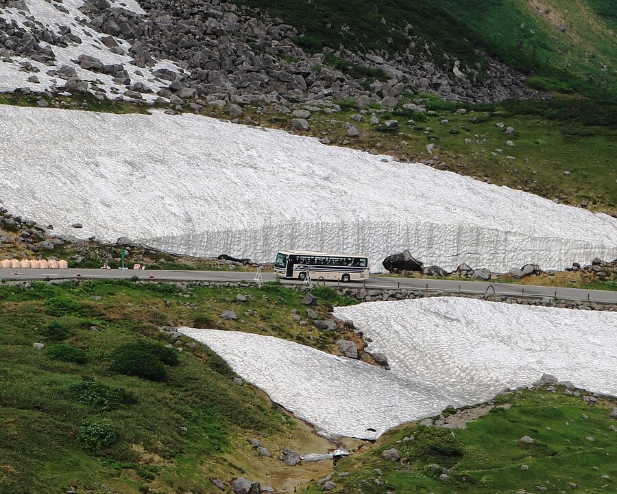 A bus driving through the Yuki-no-Otani snow corridor at Murodo