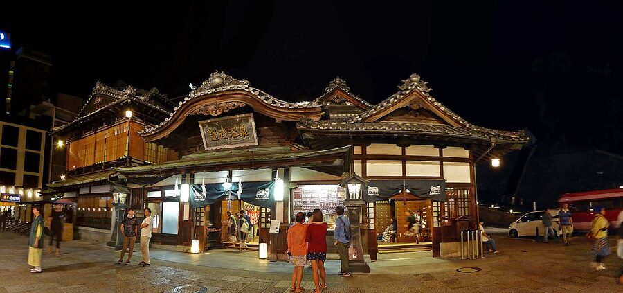 Dogo Onsen Honkan exterior in daylight, wooden balconies