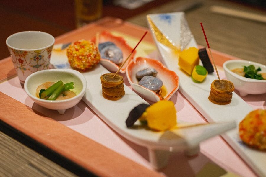 Multi-course kaiseki dinner with sashimi, vegetables and small bowls arranged on a tray
