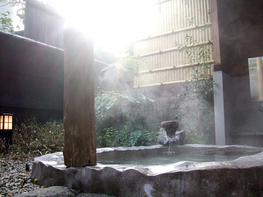 Outdoor wooden rotenburo bath at Yufuin Onsen with mountain view