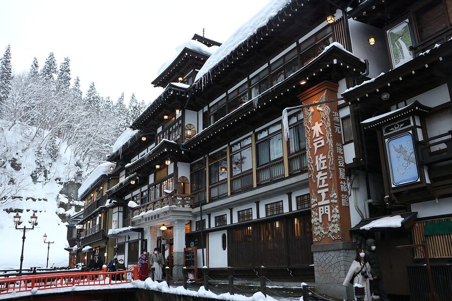 The Notoya Ryokan facade at Ginzan Onsen in January, with snow accumulated on the wooden eaves