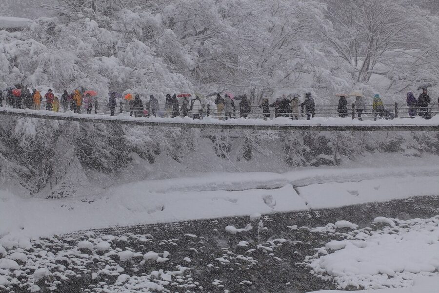 The Deai-bashi suspension bridge at Shirakawa-go in winter, with snow on the railings