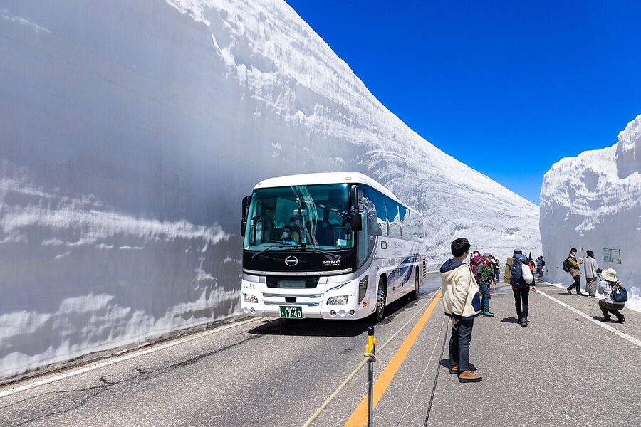 A walker dwarfed by the Yuki-no-Otani snow walls at Murodo on the Tateyama Kurobe Alpine Route in early May