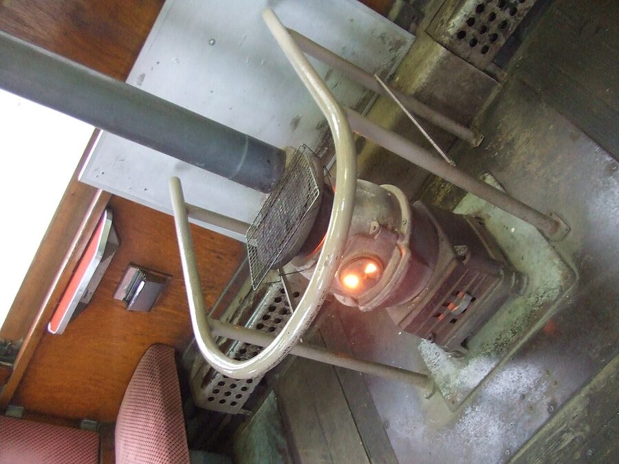 The interior of a Tsugaru Stove Train carriage, with a coal-burning daruma stove in the middle of the aisle