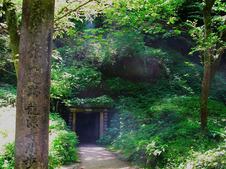 Inside the Ryugenji mine shaft at Iwami Ginzan, low arched tunnel cut into rock.