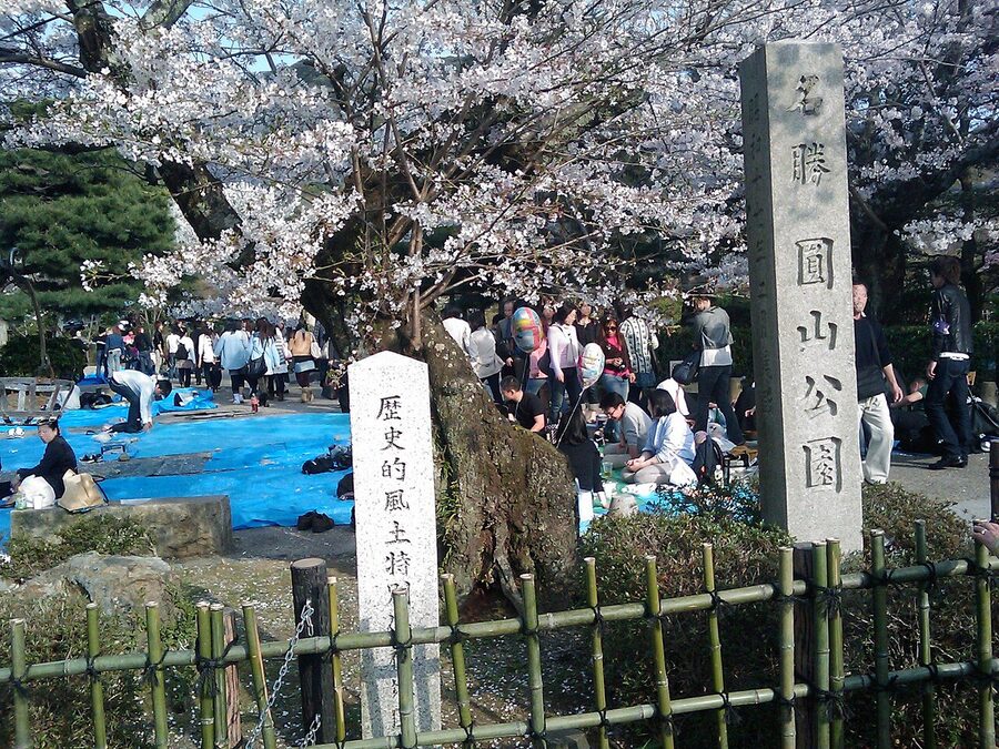 The pond at Maruyama Park surrounded by trees in early spring, with a small wooden teahouse on the far bank