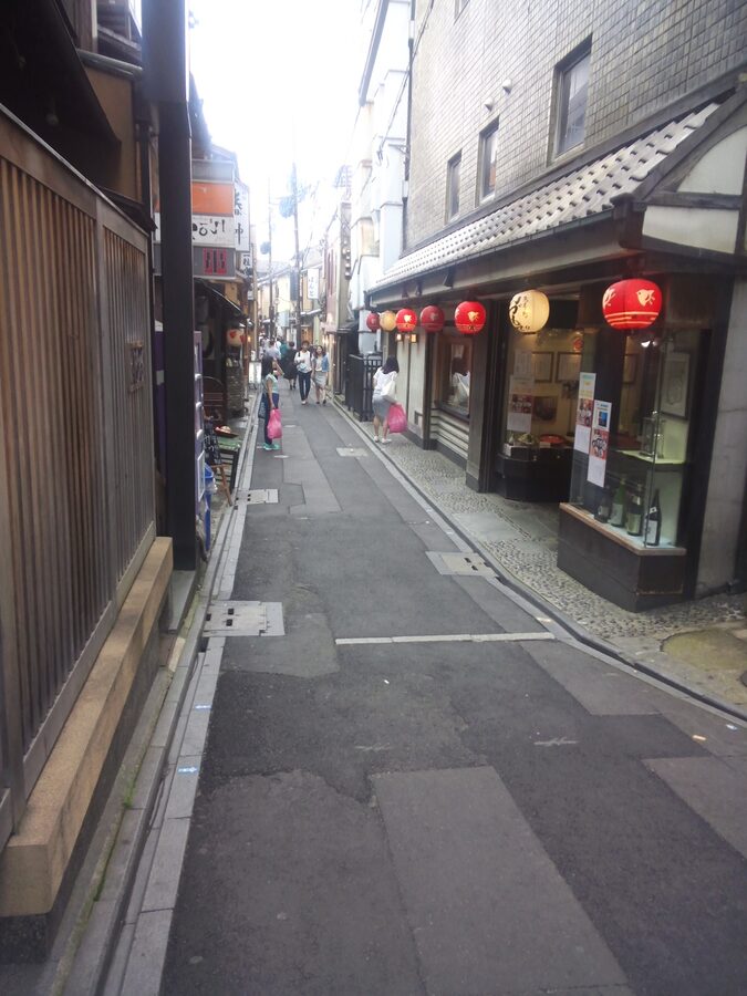 The narrow Pontocho alley at dusk, lit by lanterns, with restaurant facades on both sides
