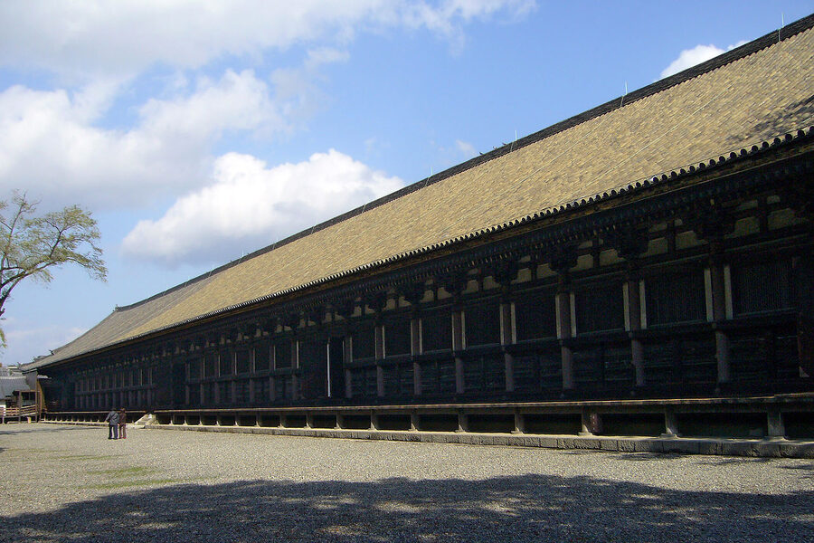 The long wooden Sanjusangendo hall stretching across a temple courtyard, with grey-tile roofs and white plaster walls