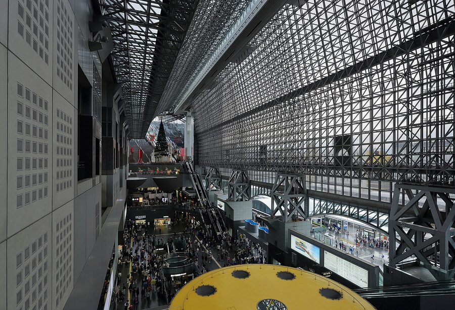 The grand staircase atrium inside Kyoto Station, with steel rafters arching above the wide concourse