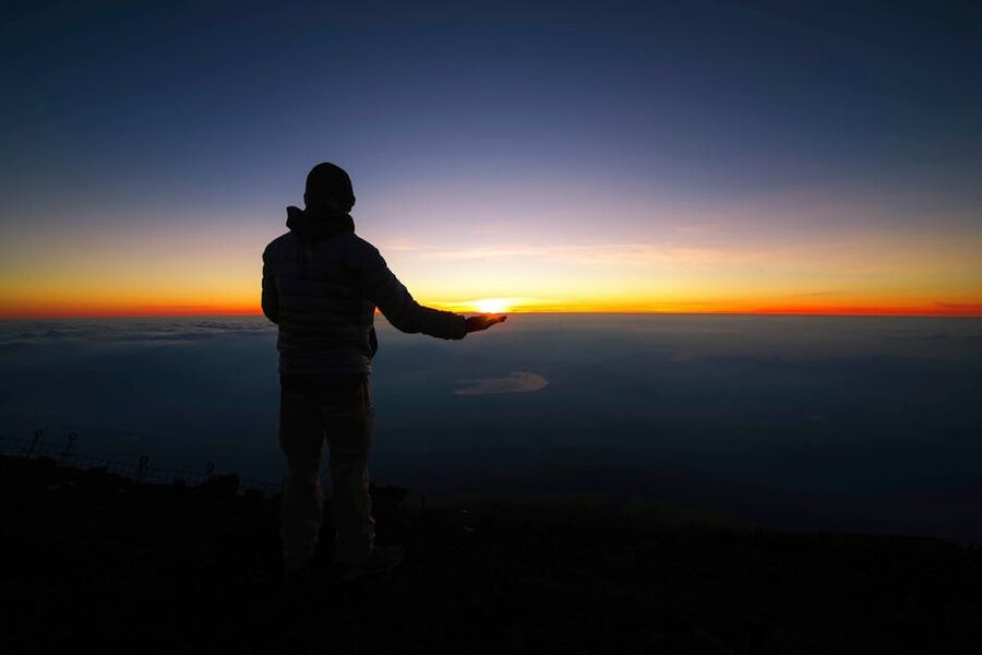 Hiker watching the sunrise from Mt Fuji