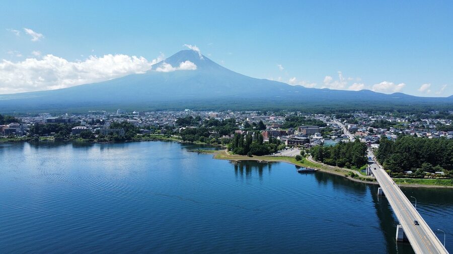 A pedestrian bridge near Kawaguchiko with Mount Fuji rising behind a clear morning sky