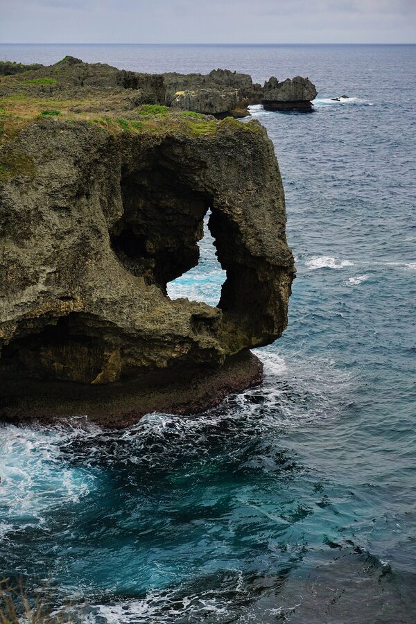 The elephant-trunk-shaped limestone cliff of Cape Manzamo above turquoise water