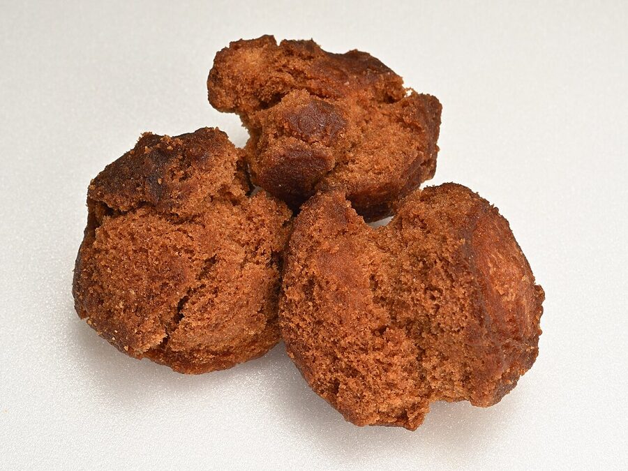Golden brown deep-fried Okinawan donuts called sata andagi piled in a paper-lined basket