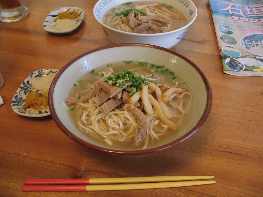 A bowl of Okinawa soba with thick wheat noodles, pork rib and pickled ginger