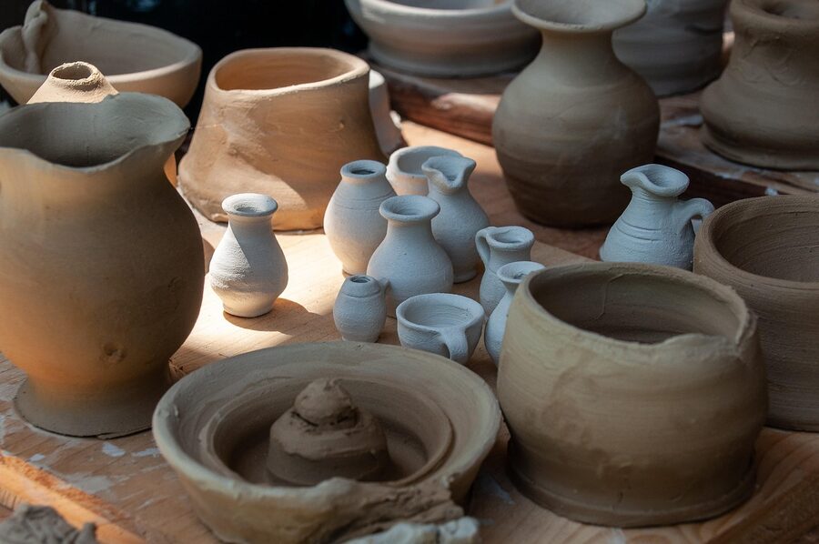 A display of yachimun pottery on a wooden shelf, glazed bowls and shisa figurines
