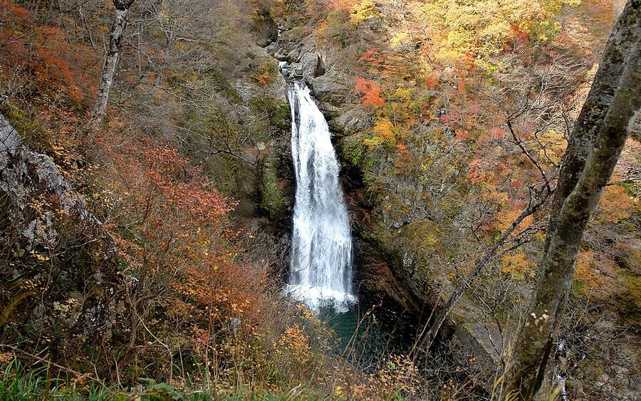 Akiu Otaki waterfall in autumn with red and orange leaves around the cascade