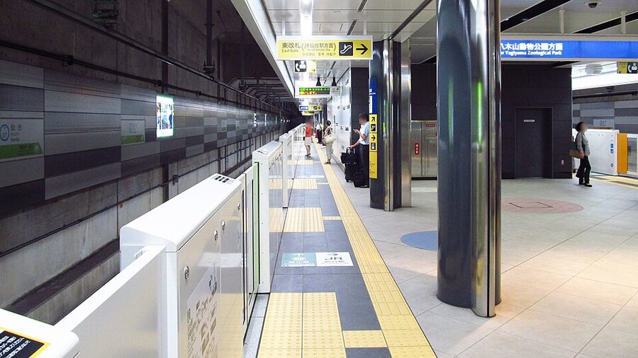 Sendai Subway Tozai Line platform with a train stopped and passengers boarding