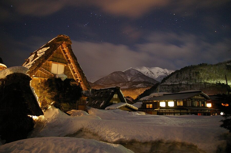 Gassho-zukuri farmhouses at Shirakawa-go reflected in still water at night during the winter light-up