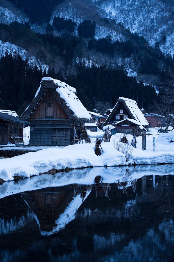 Reflection of snow-covered Shirakawa-go houses in a pond in winter